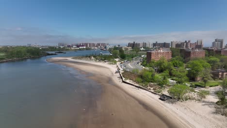 An-aerial-view-over-the-beach-on-Gravesend-Bay-in-Brooklyn,-NY-on-a-beautiful-day-with-blue-skies-and-white-clouds
