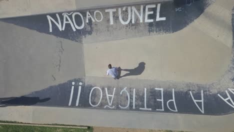 aerial-view-of-teenager-skateboarding-at-outdoor-skate-park-in-a-estoril-saying-"não-ao-túnel"-in-PDG,-Estoril,-Cascais