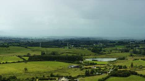 Zeitraffer-Der-Ländlichen-Landwirtschaftslandschaft-Mit-Grasfeldern,-See-Und-Hügeln-Während-Eines-Vorbeiziehenden-Sturmregentages-In-Irland