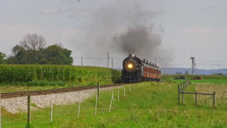 Ein-Blick-Auf-Einen-Antiken-Dampfzug,-Der-An-Einem-Sonnigen-Sommertag-Rauch-Und-Dampf-Durch-Fruchtbare-Maisfelder-Bläst