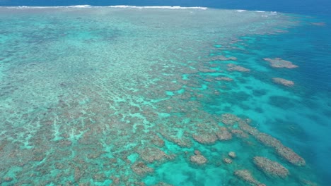 Great-Barrier-Reef-backward-aerial-of-coral-ecosystem-and-colorful-water,-near-Cairns,-Queensland,-Australia