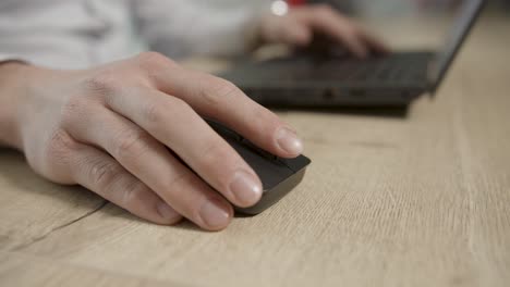 Caucasian-male-use-wireless-black-mouse-on-wooden-table-for-computer-work