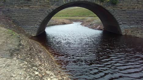Pequeño-Puente-En-Los-Páramos-De-Yorkshire-Con-El-Río-Manchado-De-Turba-Que-Pasa