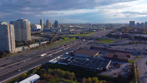 Drone-hyperlapse-of-Highway-401-and-Scarborough-Town-Centre-in-Toronto,-Ontario-showing-busy-traffic-and-transportation-trucks