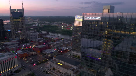 Aerial-view-around-the-Bridgestone-building,-overlooking-the-Broadway-street,-dusk-in-Nashville,-USA---circling,-drone-shot