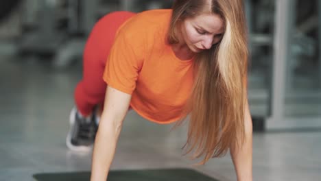 Young-pretty-woman-squeezes-off-the-floor-in-the-gym