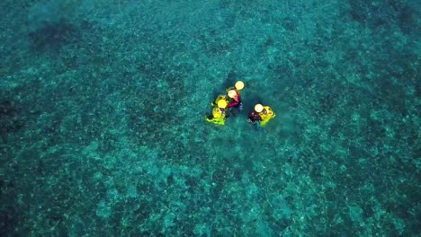 Tilt-up-aerial-view-of-two-people-holding-yellow-diving-bells,-Pirate-Bay-Club,-Dutch-island-of-Curacao,-Caribbean-Sea