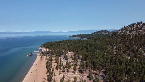 Counterclockwise-drone-shot-of-Nevada-Beach,-the-surrounding-forest,-and-Lake-Tahoe-on-a-beautiful-day-in-Nevada