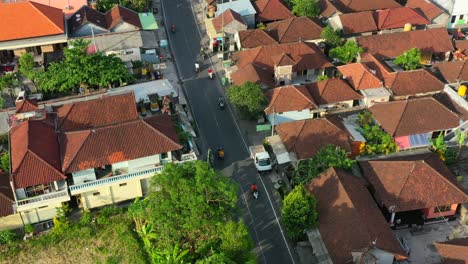 aerial-top-down-of-motorbikes-driving-on-a-local-neighborhood-road-in-Bali-Indonesia-at-sunset