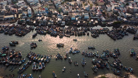 Vietnamesische-Stadtgebäude-Und-Viele-Fischerboote,-Die-An-Der-Flussküste-Festgemacht-Sind