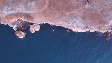 Luftaufnahme-Von-Oben-Nach-Unten-Von-Wellen-Gegen-Felsige-Küste,-Hintergrund