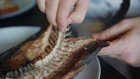 Restaurant-client-removes-bone-from-grilled-fish,-close-up-slow-motion