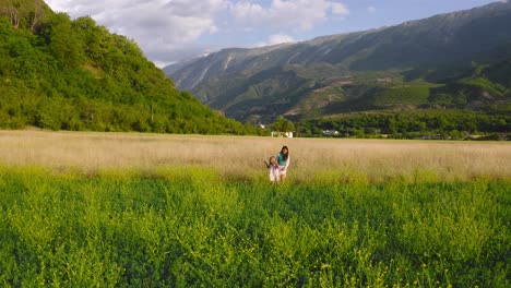 mother-and-daughter-stroll-along-beautiful-flowering-field-in-Permet-valley,-Albania