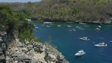 aerial-revealing-a-tropical-white-sand-beach-at-crystal-bay-with-boats-anchored-in-nusa-penida-bali