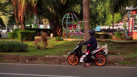man-jacket-sits-on-a-motorcycle-next-to-city-park,-Semarang,-Central-Java,-Indonesia-on-June-10,-2022