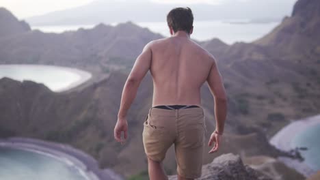 Man-is-enjoying-the-view-of-nature-on-top-of-a-hill-without-a-shirt-on
