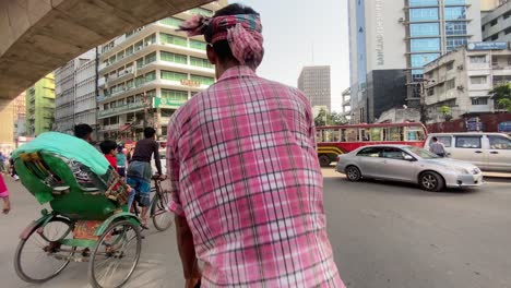 Pov-wide-view-of-Rickshaw-puller-pulling-Rickshaw-at-a-busy-city-road-in-Dhaka,-Bangladesh