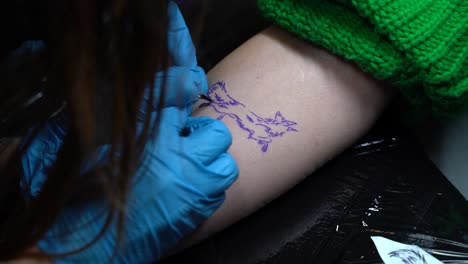 The-tattoo-artist-is-tattooing-a-fox-on-a-woman's-hand