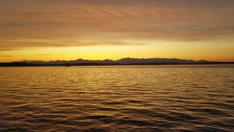 Blick-Auf-Einen-See-Während-Des-Sonnenuntergangs,-Ruhiges-Und-Friedliches-Wasser-Reflektiert-Die-Sonnenstrahlen,-Während-Hügel-In-Der-Ferne-Sichtbar-Sind