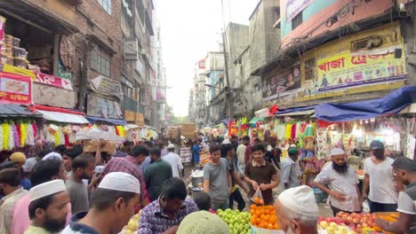 Aufnahme-Von-Einheimischen,-Die-Damit-Beschäftigt-Sind,-Früchte-Von-Einem-Sehr-Geschäftigen-Traditionellen-Iftar-Markt-In-Dhaka,-Bangladesch,-Zu-Kaufen,-Mit-Reihen-Von-Geschäften-Auf-Beiden-Seiten-Im-Hintergrund-Tagsüber