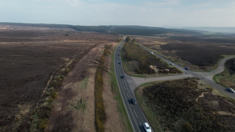 Aerial-view-above-vehicles-driving-long-straight-road-through-rural-Goathland-North-Yorkshire-moorland-countryside
