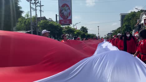 The-stretching-of-the-long-red-and-white-Indonesian-flag-was-carried-by-several-people-through-the-landmark-area-of-the-Tugu-Yogyakarta-monument,-in-the-context-of-Indonesia's-independence