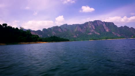 Speeding-Across-Cheow-Lan-Lake-With-View-Of-Limestone-Cliffs-In-The-Background-At-Khao-Sok-National-Park,-Thailand
