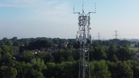 5G-broadcasting-tower-antenna-in-British-countryside-woodland-landscape-aerial-dolly-rising-right-view