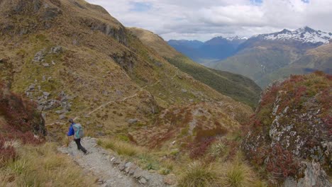 Tilt-up,-hiker-descends-exposed-alpine-pass,-Routeburn-Track-New-Zealand