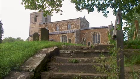 Old-worn-stone-steps-leading-up-to-the-12th-century-old-English-church-in-a-beautiful-old-English-rural-village-in-the-United-Kingdom