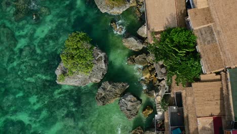Luftaufnahme-Von-Oben-Nach-Unten-Von-Häusern-An-Den-Klippen-An-Der-Felsigen-Küste-In-Uluwatu-Bali-Mit-Türkisfarbenem-Ozean