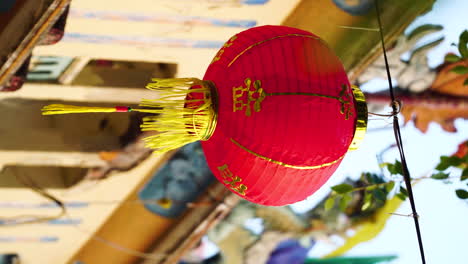 Close-up-of-Chinese-red-paper-lantern-swaying-in-wind