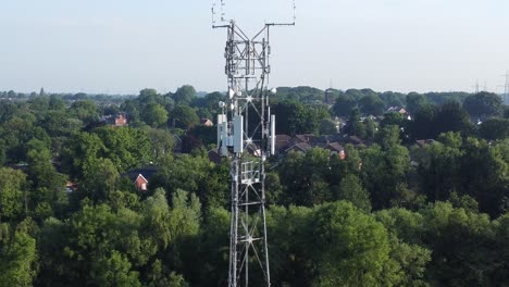 5G-broadcasting-tower-antenna-in-British-countryside-aerial-orbit-right-across-woodland-landscape