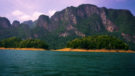 Sailing-Past-Small-Islands-On-Cheow-Lan-Lake-With-View-Of-Limestone-Cliffs-At-Khao-Sok-National-Park,-Thailand