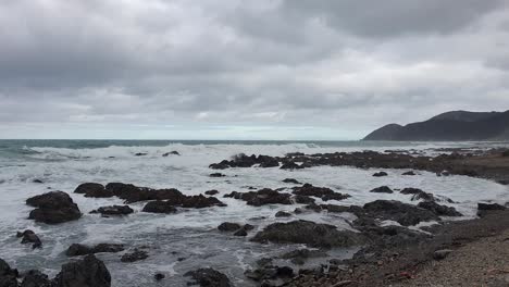 Wild-white-wash-waves-crashing-over-rocks-along-beautiful-rugged-remote-coastline-in-Wellington,-New-Zealand-Aotearoa