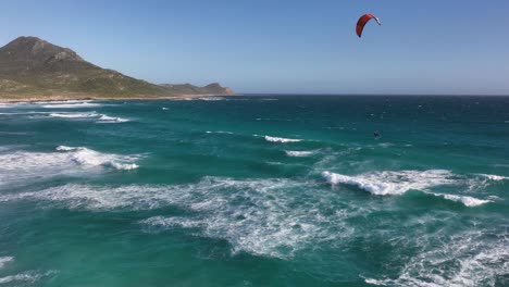 Luftdrohnenaufnahme-In-Zeitlupe-Eines-Kitesurfers,-Der-Am-Kap-Der-Guten-Hoffnung-Im-Cape-Point-National-Park-In-Kapstadt-Massive-Luft-Bekommt