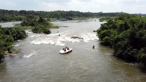 Vista-Aérea-De-Drones-De-Un-Bote-De-Rafting-Al-Revés-Con-Gente-Encima-En-El-Río-Nilo-En-Jinja,-Uganda
