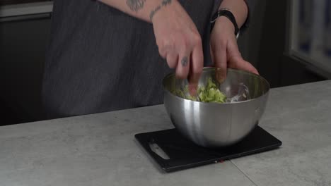 Chef-mixes-cottage-cheese-and-shredded-cucumber-in-metal-mixing-bowl