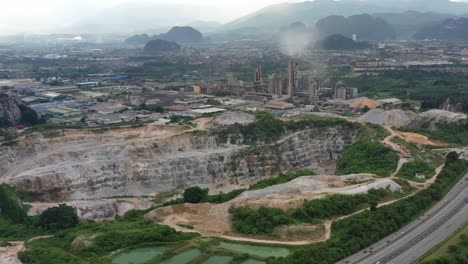 Aerial-drone-fly-around-active-limestone-quarrying-operation-and-production-site,-destroying-nature-in-returns-of-natural-resources-for-economy-purpose,-at-ipoh,-perak-state,-malaysia,-southeast-asia