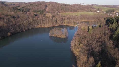 Aerial-footage-of-a-blue-lake-within-a-brown-winter-landscape-at-sunset