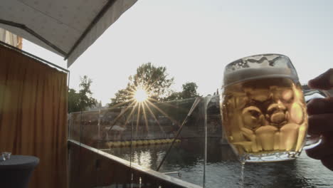Beer-glasses-clinking-in-front-of-Charles-Bridge-with-sunset-in-background