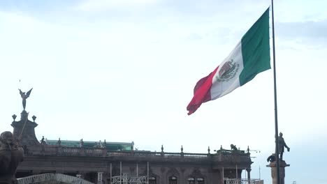 Mexican-flag-slow-motion-waving-in-windy-day-with-against-clear-blue-sky