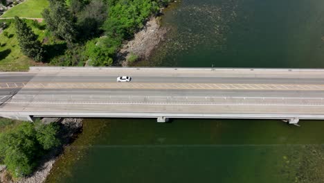 Overhead-drone-shot-of-a-car-driving-over-a-river-in-Washington