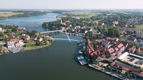 Mikolajki,-Poland---Aerial-bird-view-flight-over-the-pedestrian-bridge-most-wiszacy-of-the-touristic-city-in-Warmian-Masurian-with-romantic-houses-along-the-sea-and-tiny-ships-and-yachts-in-summer