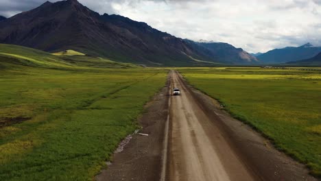 Road-trip-on-a-van-through-Portage-valley-by-the-Brooks-Range-mountains-in-Summer-Alaska---Aerial-tracking-shot-with-a-backward-motion