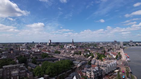 Aerial-ascending-movement-revealing-cityscape-of-Dutch-historic-Hanseatic-city-center-of-Nijmegen-in-The-Netherlands-on-riverbed-of-river-Maas-on-a-sunny-day-partly-in-shadow-of-clouds