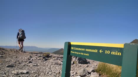 Static,-hiker-nearby-Mt-Luxmore-Summit-sign,-Kepler-Track-New-Zealand
