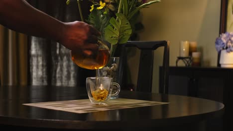 Mittlere-Rückansicht-Eines-Afroamerikanischen-Mannes,-Der-Tee-In-Eine-Teetasse-Aus-Glas-Gießt