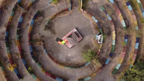 Aerial-descending-circling-view-over-colorful-labyrinth-with-central-wooden-structure-in-children-playground