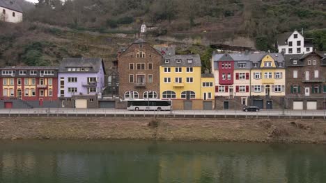 Static-shot-of-busses-and-cars-going-by-typical-old-German-houses-along-the-moselle-river-in-Cochem,-Rhineland-Palatinate